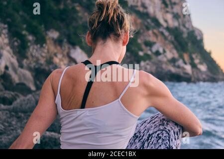 Anonymer weiblicher Körper auf Felsen in der Nähe des Meeres Stockfoto