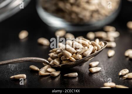 Geschälte Sonnenblumenkerne in Silberlöffel auf schwarzem Tisch Stockfoto