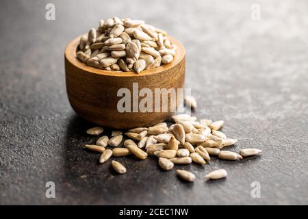 Geschälte Sonnenblumenkerne in Holzschale auf schwarzem Tisch. Stockfoto
