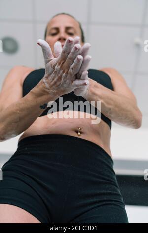 Von unten Aufnahme einer Frau, die während des Trainings im Fitnessstudio Kreide auf die Hände streut Stockfoto