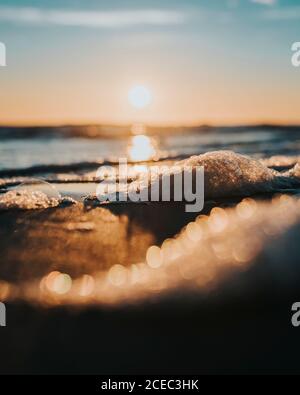 Nahaufnahme schmelzender Eisstücke an der Küste und das Wasser bei Sonnenuntergang. Stockfoto
