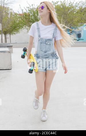 Blonde Mädchen mit Penny Board zu Fuß im Park Stockfoto