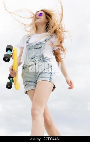 Blonde Mädchen mit Penny Board zu Fuß im Park Stockfoto