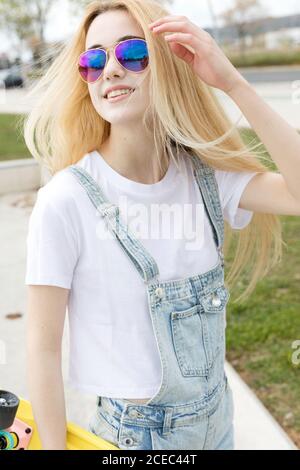 Blonde Mädchen mit Penny Board zu Fuß im Park Stockfoto