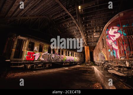 Alte verlassene Waggons mit Graffiti auf der Oberfläche stehen in überdacht Depot Stockfoto