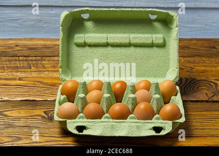 Dutzend Eier in grüner Pappverpackung auf Holztisch Nahaufnahme. Stockfoto