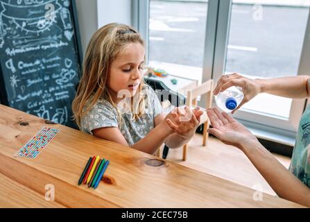 Lehrer in der Schule unterrichtet Mädchen, Hände zu desinfizieren Stockfoto