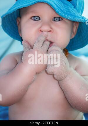 Junge Kleinkind Junge in Panama hat Finger mit Sand lecken und Blick auf die Kamera. Stockfoto