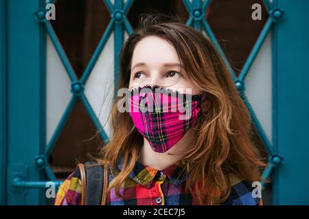 Nahaufnahme Porträt einer jungen Frau in einem karierten handgefertigten Gesichtsmaske auf altem blauen Türhintergrund Stockfoto