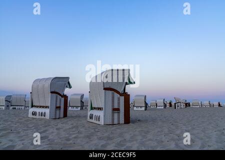 Ein wunderschöner Sonnenuntergang und Strandabend mit weißen Strandkörben Am Sandstrand Stockfoto