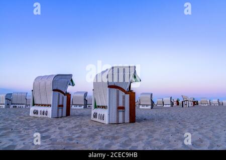 Ein wunderschöner Sonnenuntergang und Strandabend mit weißen Strandkörben Am Sandstrand Stockfoto