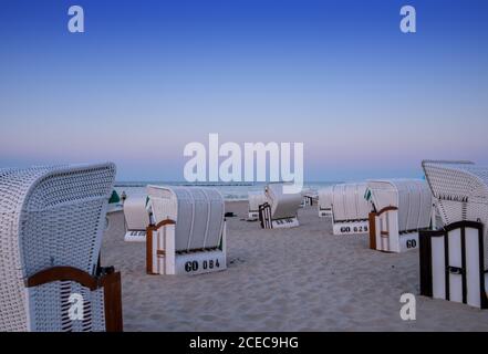 Ein wunderschöner Sonnenuntergang und Strandabend mit weißen Strandkörben Am Sandstrand Stockfoto