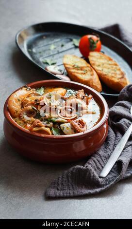 Suppe von Tintenfisch und Garnelen in der Nähe von Toast und Löffel Stockfoto