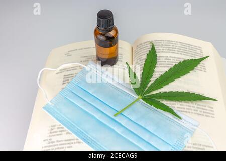 Ansicht eines offenen Buches mit einem Cannabisblatt Top und ein cbd-Extrakt in einem Glas Stockfoto
