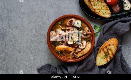 Suppe von Tintenfisch und Garnelen in der Nähe von Toast und Löffel Stockfoto