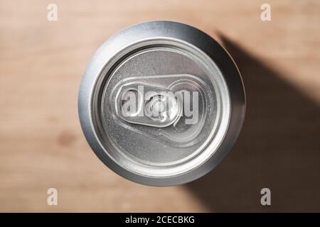Geschlossene glänzende Aluminium-Dose steht auf einem Holztisch, Standard-Softdrink-Verpackung. Draufsicht Stockfoto