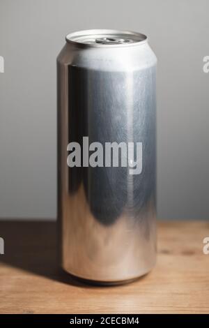 Geschlossene glänzende Aluminium-Dose steht auf einem Holztisch, Standard-Softdrink-Verpackung Stockfoto