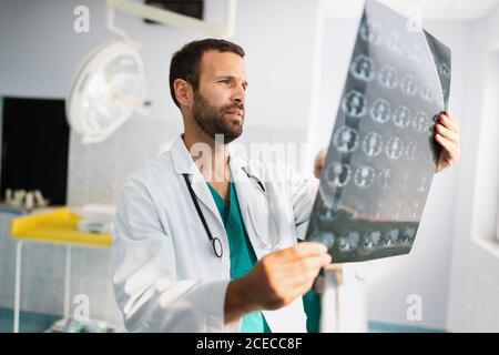 Porträt des jungen Arztes, der Röntgenaufnahmen im Krankenhaus überprüft, um eine Diagnose zu stellen Stockfoto