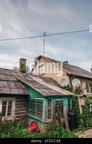 Kleines Holzhaus, das in der Nähe von Ziegelstein auf dem Hintergrund steht wolkiger Himmel in erstaunlichen ländlichen Siedlung Stockfoto