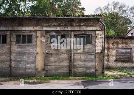 Altes Gebäude mit schäbigen Backsteinwänden und Holztüren Auf der Straße der kleinen Siedlung Stockfoto