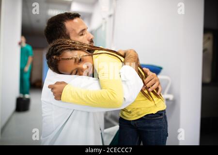 Arzt, der mit einem traurigen kleinen Mädchen im Krankenhaus zu sprechen hat. Arzt tröstet Kind Stockfoto
