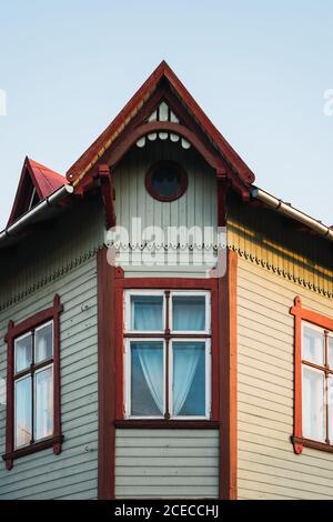 Schöne Fenster unter Zierdach des alten Hauses auf Hintergrund des blauen Himmels in einer kleinen Stadt Stockfoto