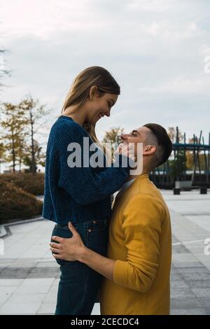 Seitenansicht von trendigen Männern und Frauen, die sich auf der Straße umarmen und anguckend. Stockfoto