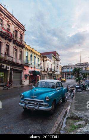 LA HABANA, KUBA - 6. NOVEMBER , 2018: Oldtimer auf Straße in der Nähe?Gebäude zwischen Bäumen und männlich an sonnigen Tagen in Kuba Stockfoto