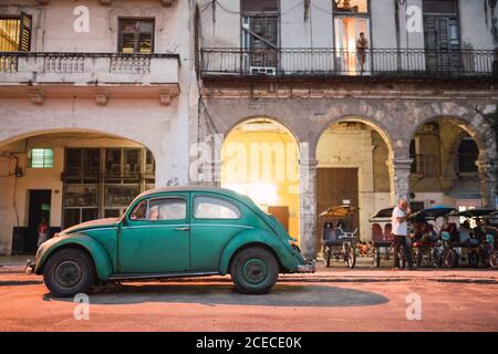 LA HABANA, KUBA - 6. NOVEMBER , 2018: Seitenansicht Oldtimer auf der Straße in der Nähe von Rikschas, alten Häusern und Männchen in Kuba Stockfoto