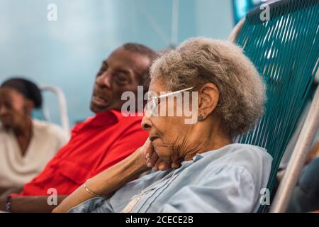 LA HABANA, KUBA - 6. NOVEMBER , 2018: Seitenansicht Afroamerikaner Frauen und Männer sitzen und schlafen im Zimmer in Kuba Stockfoto