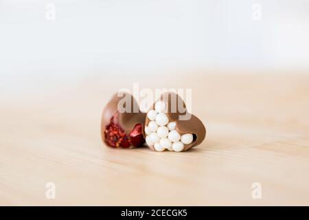 Belgisches Handwerk herzförmige Schokolade Süßigkeiten mit roten und weißen Füllung Liegen Sie auf einem Holztisch Stockfoto