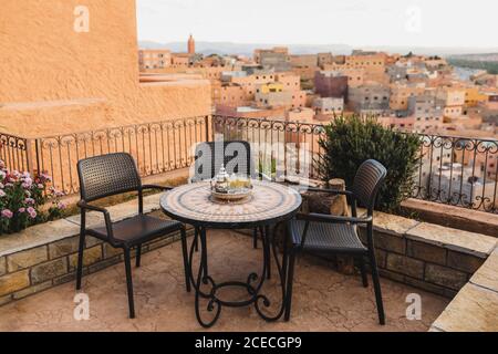 Runder Mosaiktisch auf der Terrasse mit traditionellem marokkanischen Minztee. Tolle Aussicht auf die Altstadt von Boumalne in Marokko bei Sonnenuntergang. Stockfoto