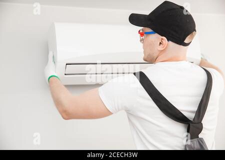 Techniker Mann Arbeiter Reparatur und installiert Klimaanlage an der weißen Wand Stockfoto
