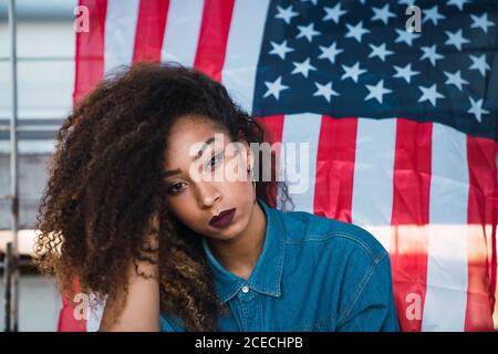 Junge Frau, die in der Nähe der Flagge Amerikas sitzt Stockfoto