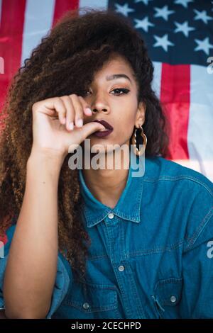 Junge Frau, die in der Nähe der Flagge Amerikas sitzt Stockfoto