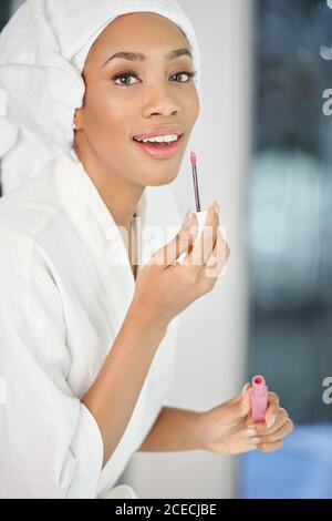 Portrait der schönen jungen schwarzen Frau im Bademantel Anwendung Licht Rosa Lippenstift Stockfoto