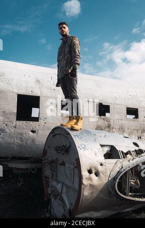 Mann, der auf einem alten zerstörten Flugzeug steht Stockfoto