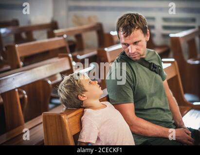 Christian Papa erzählt seinem Sohn biblische Geschichten über Jesus in kirk sitzen. Glaube, Religionsunterricht, moderne Kirche, Vatertag, väterliche Stockfoto