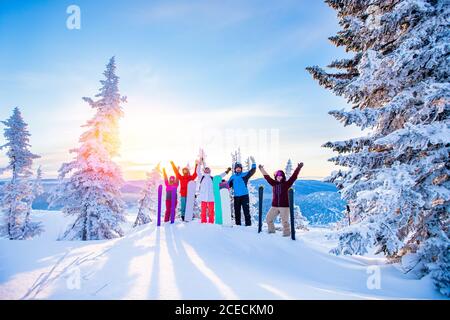 Eine Gruppe von Snowboardern und Skifahrerfrühs mit Snowboards freut sich über die Sonne im Winterwald bei Sonnenaufgang. Konzept Lebensstil, Reisen Stockfoto