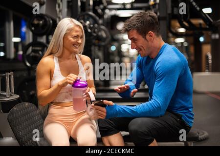 Mann und Frau sitzen im Fitnessstudio und lachen Stockfoto