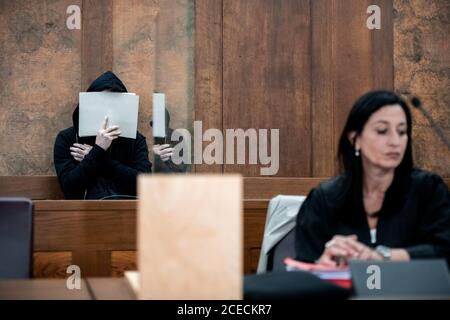 01. September 2020, Nordrhein-Westfalen, Duisburg: Die Anwältin der Angeklagten, Simone Dahlmann-Ludwig, sitzt im Gerichtssaal vor dem Angeklagten, der sein Gesicht versteckt. Der Prozess gegen den gewaltsamen Tod einer 26-jährigen Frau beginnt am Landgericht Duisburg. Der Angeklagte ist ein 29-jähriger Mann, der seine Frau am 7. September 2019 nach einem Streit in der Duisburger Wohngemeinschaft erwürgt haben soll. Er soll die Leiche in einem Wald begraben haben, wo sie etwa drei Monate später von der Polizei gefunden wurde. Mutmaßlicher Hintergrund des Verbrechens: Die 26-jährige Frau soll das beabsichtigt haben Stockfoto