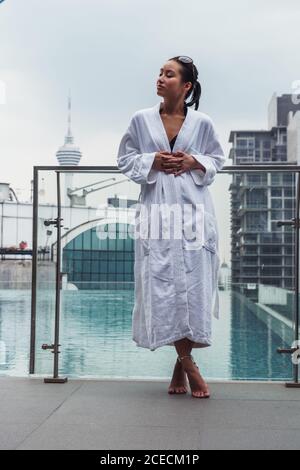 Frau im Bademantel am Pool Stockfoto