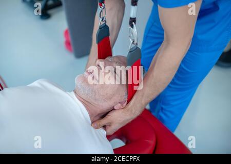 Ruhiger älterer Mann und Arzt, der eine Nackenmassage gibt Stockfoto