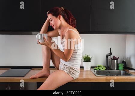 Frau trinkt Kaffee in der Küche Stockfoto
