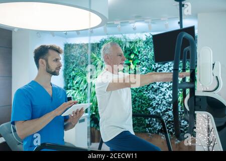 Mann, der auf dem Laufband läuft und Rehabilitationstherapeut beobachtet Stockfoto