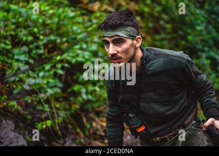 Soldat oder revolutionäres Mitglied oder Jäger in Tarnung in der Nähe der Stream Trinken natürliches sauberes Wasser aus dem Bach Stockfoto