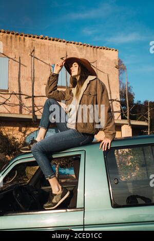 Frau, die auf dem Autodach sitzt Stockfoto