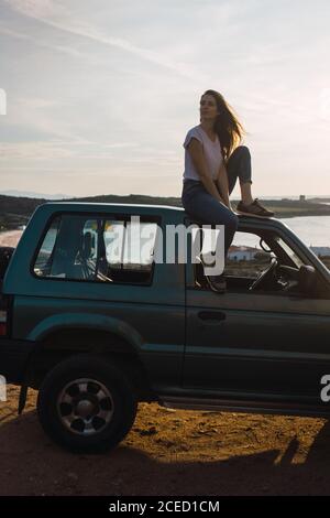 Frau, die auf dem Autodach sitzt Stockfoto