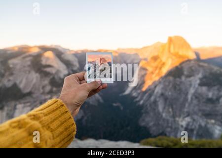 Crop Hand des Menschen halten Schuss und malerischen Blick auf Berge bei Sonnenaufgang im Yosemite Stockfoto