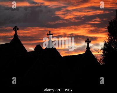 Die Kreuze der St. Bartholomäus Kirche in Shapwick, Dorset, Großbritannien, silhouetted gegen den glühenden Sonnenuntergang Himmel. Stockfoto